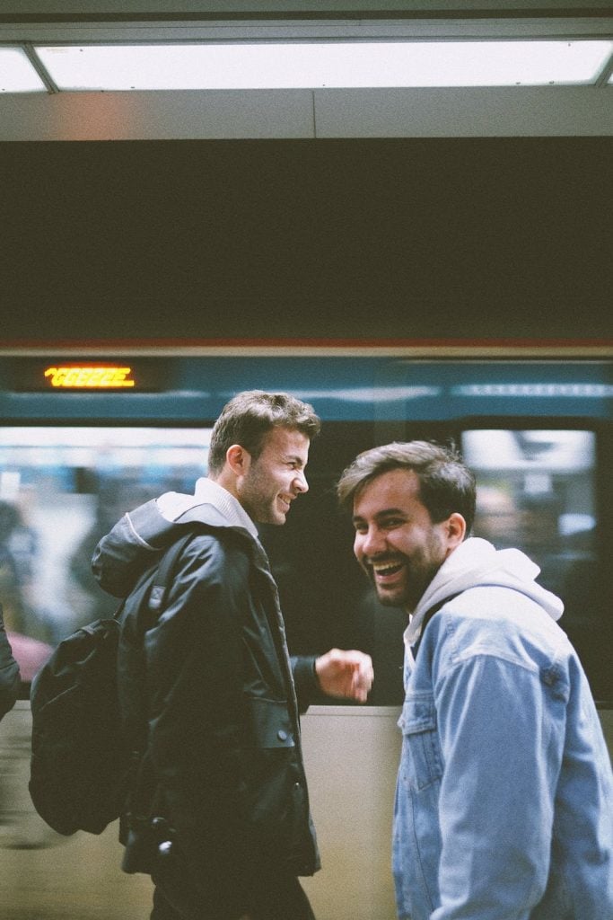 Two guys laughing inside a subway station.