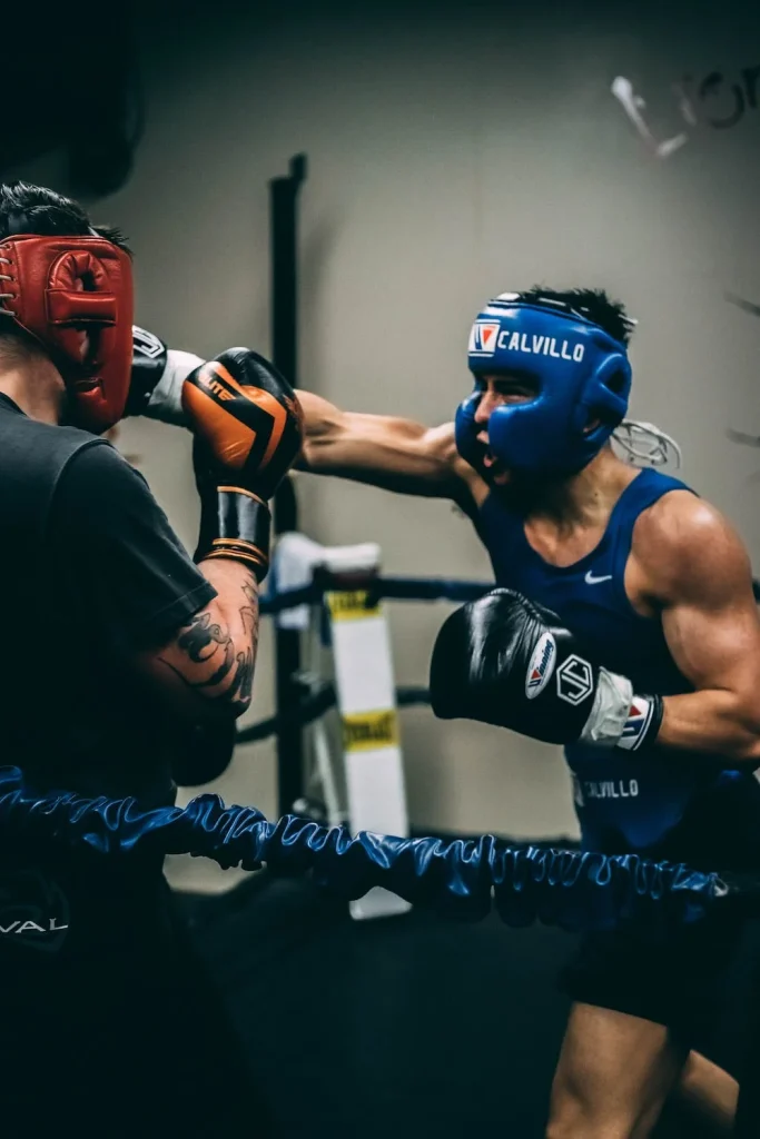 Two men boxing in a gym ring - one in blue and the other in red.