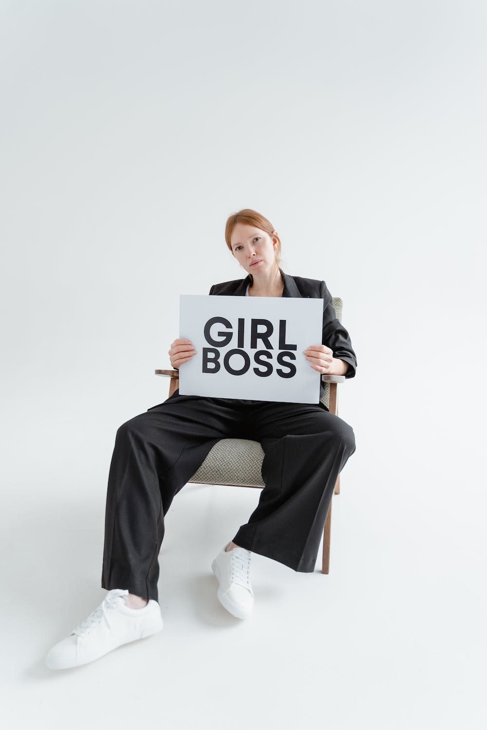 Confident girl in business suit holding a sign that says "girl boss"