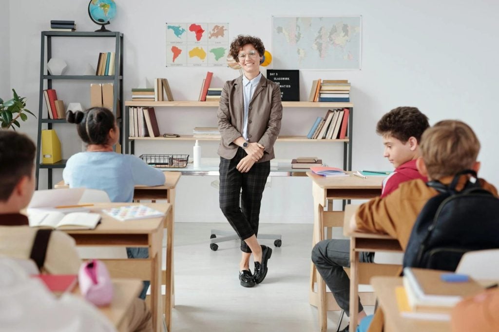 teacher standing in front of young children in class with curly hair