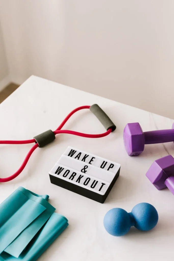 A white sign that says wake up and work out surrounded by fitness equipment on a white table