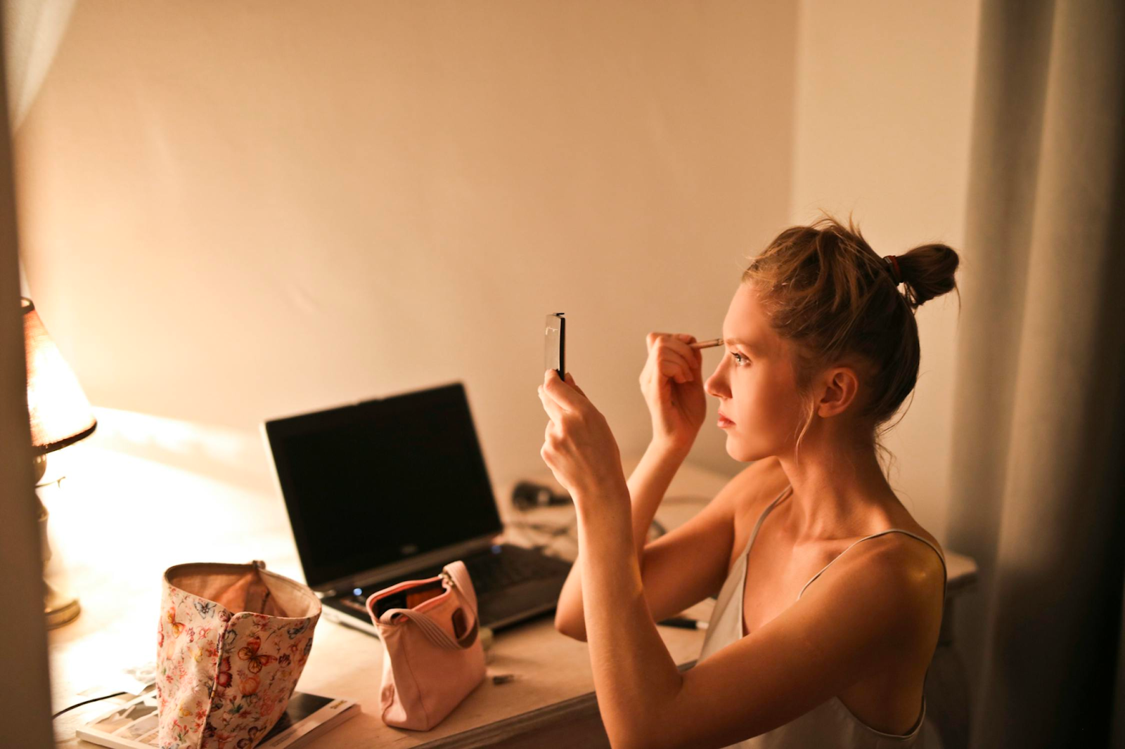 girl sitting at her desk doing makeup in front of a smartphone