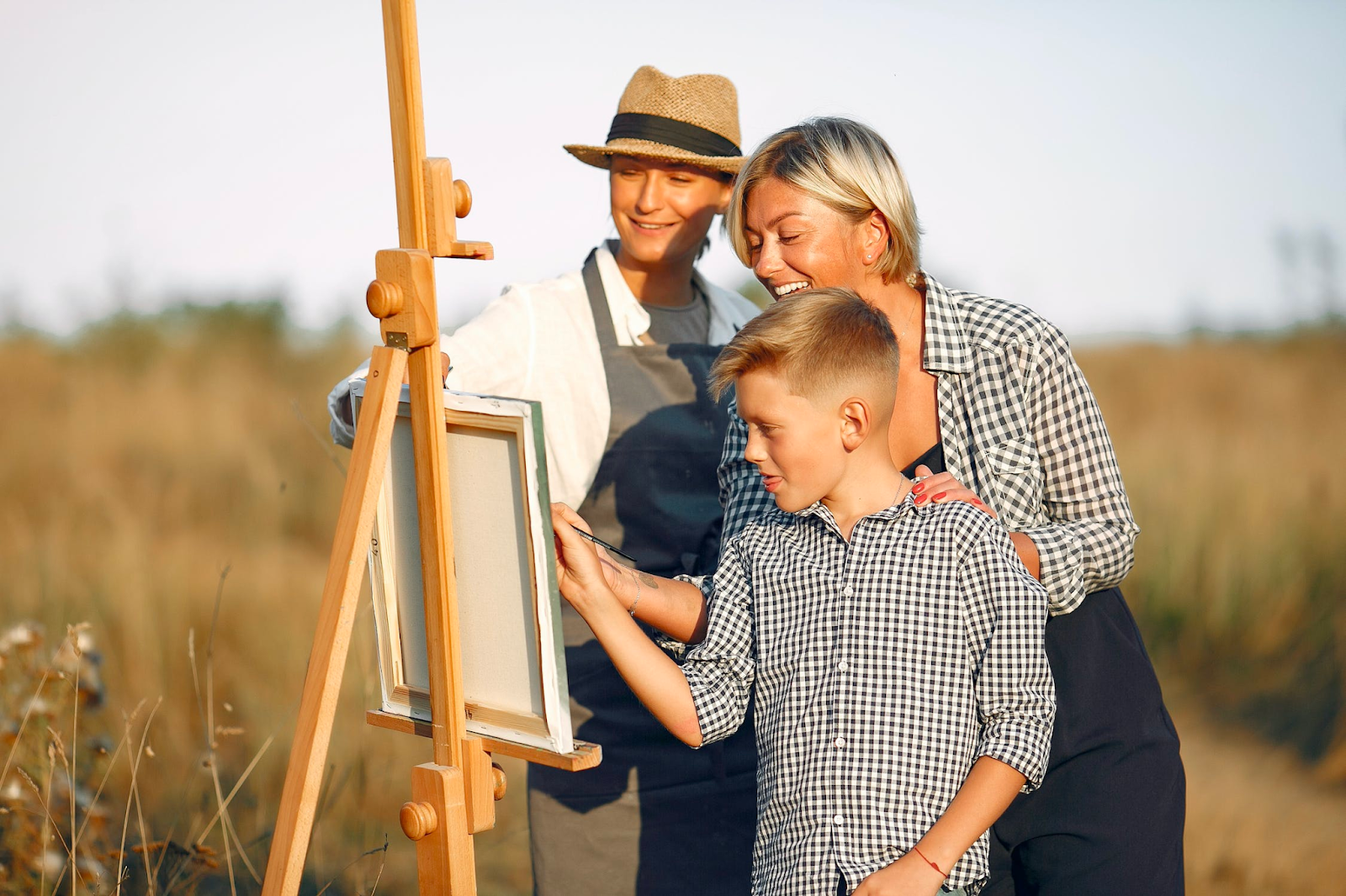 A family gathered around an easel laughing at the picture they're painting