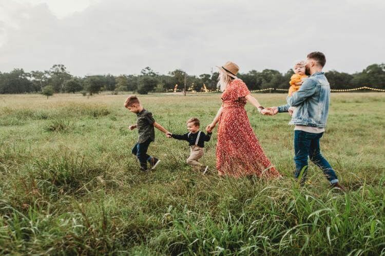 A family of five walking in a grassy field