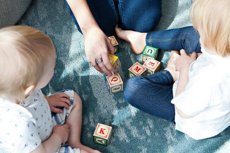 Parent teaching kids with letter blocks
