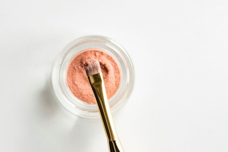 simple photo of blush powder and a brush with a white background